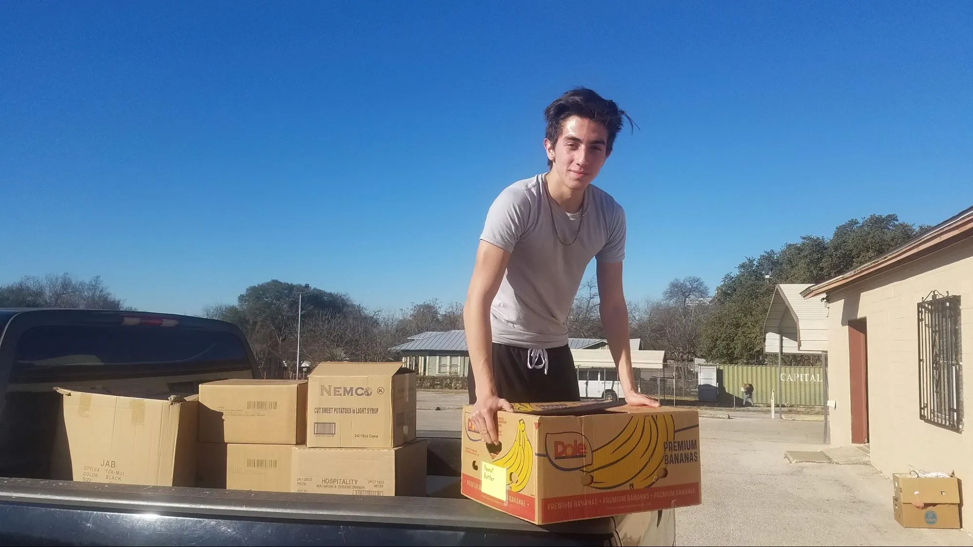 A young volunteer unloads boxes of donated food from a pickup truck