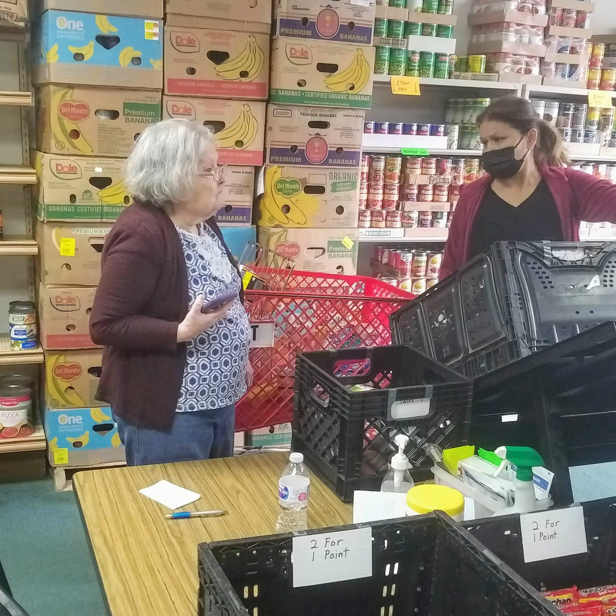 Two volunteers talk in the stocked food pantry